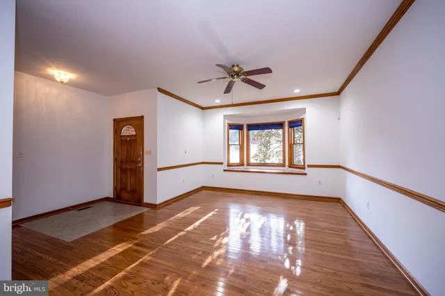 a view of an empty room with a window and wooden floor