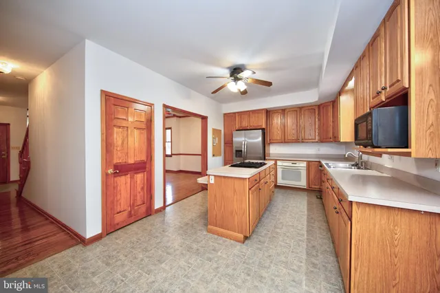 a large kitchen with stainless steel appliances granite countertop a stove a sink dishwasher and a refrigerator with wooden floor