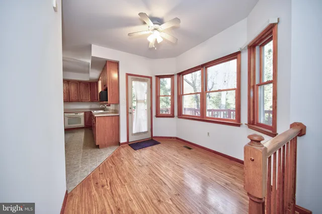 a view of an empty room with a window and a kitchen
