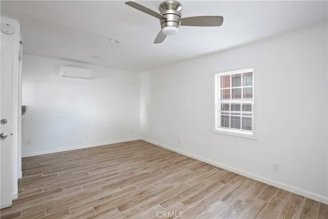 an empty room with wooden floor cabinet and windows