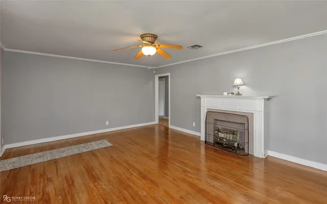 an empty room with wooden floor a fireplace and window