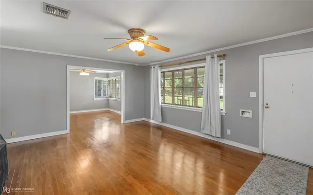 an empty room with wooden floor and windows