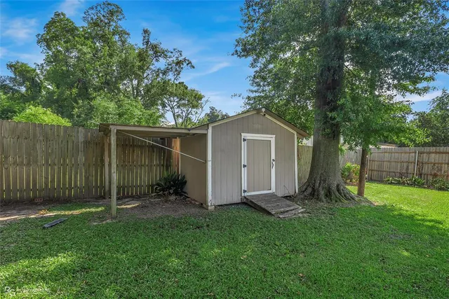 a view of a backyard with plants and large trees with wooden fence