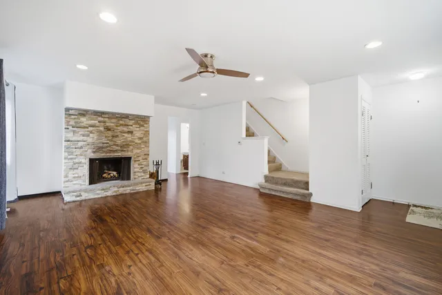 a view of an empty room with wooden floor fireplace and a window