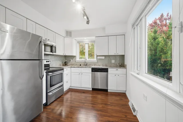 a kitchen with granite countertop white cabinets and white stainless steel appliances