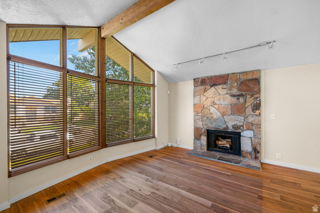 2088 Falcon Way Sandy, UT 84093 - Photo 13 of 46 Vaulted ceiling with exposed wood beam, a stone-clad fireplace, and track lighting
