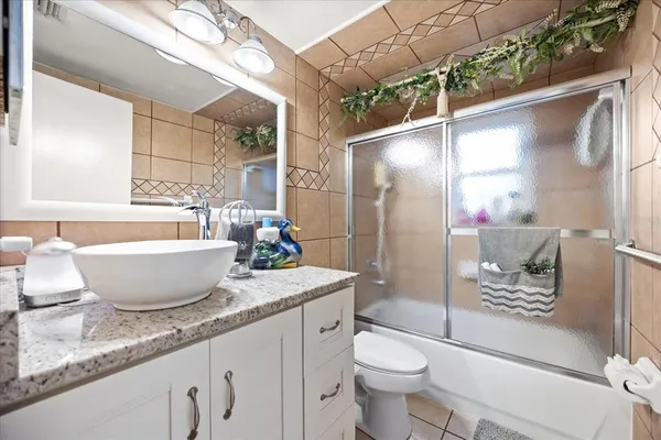 a bathroom with a granite countertop sink a toilet a mirror and shower