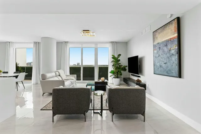 a living room with couches a flat screen tv and a large window