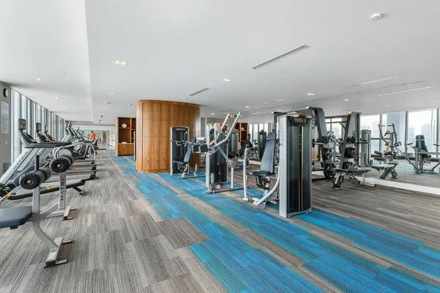 a view of a room with gym equipment wooden floor and a large window