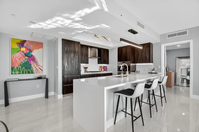 a kitchen with stainless steel appliances kitchen island granite countertop a sink and a refrigerator
