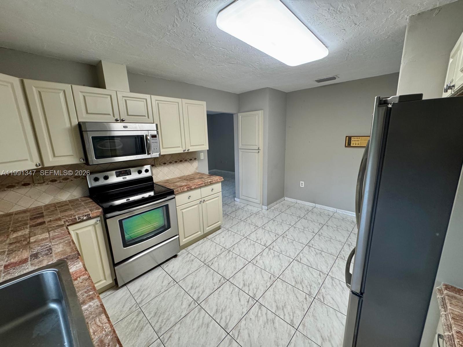 2505 Southwest 126th Avenue Miami, FL 33175 - Photo 8 of 22 a kitchen with granite countertop a refrigerator and a stove top oven