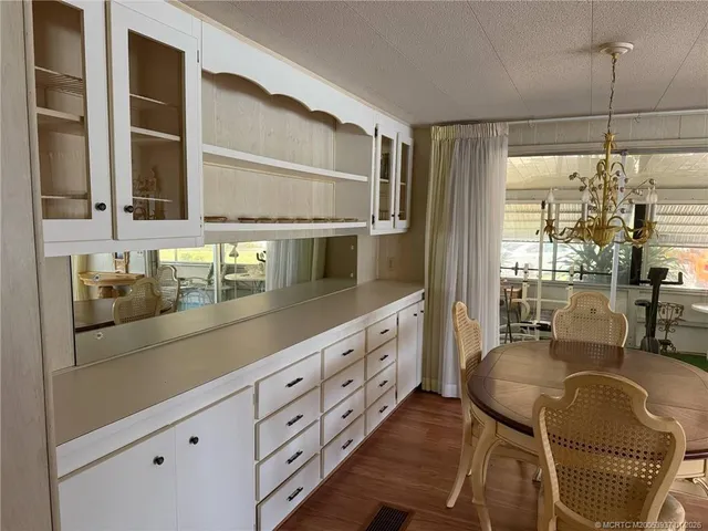 a kitchen with stainless steel appliances granite countertop a stove a sink and a dining table with white cabinets