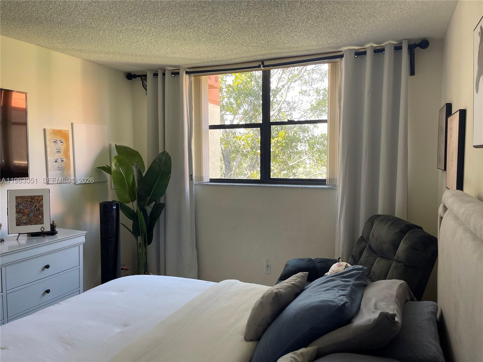 16475 Golf Club Road, Unit 309 Weston, FL 33326 - Photo 22 of 36 a bedroom with a bed wooden floor and a flat tv screen