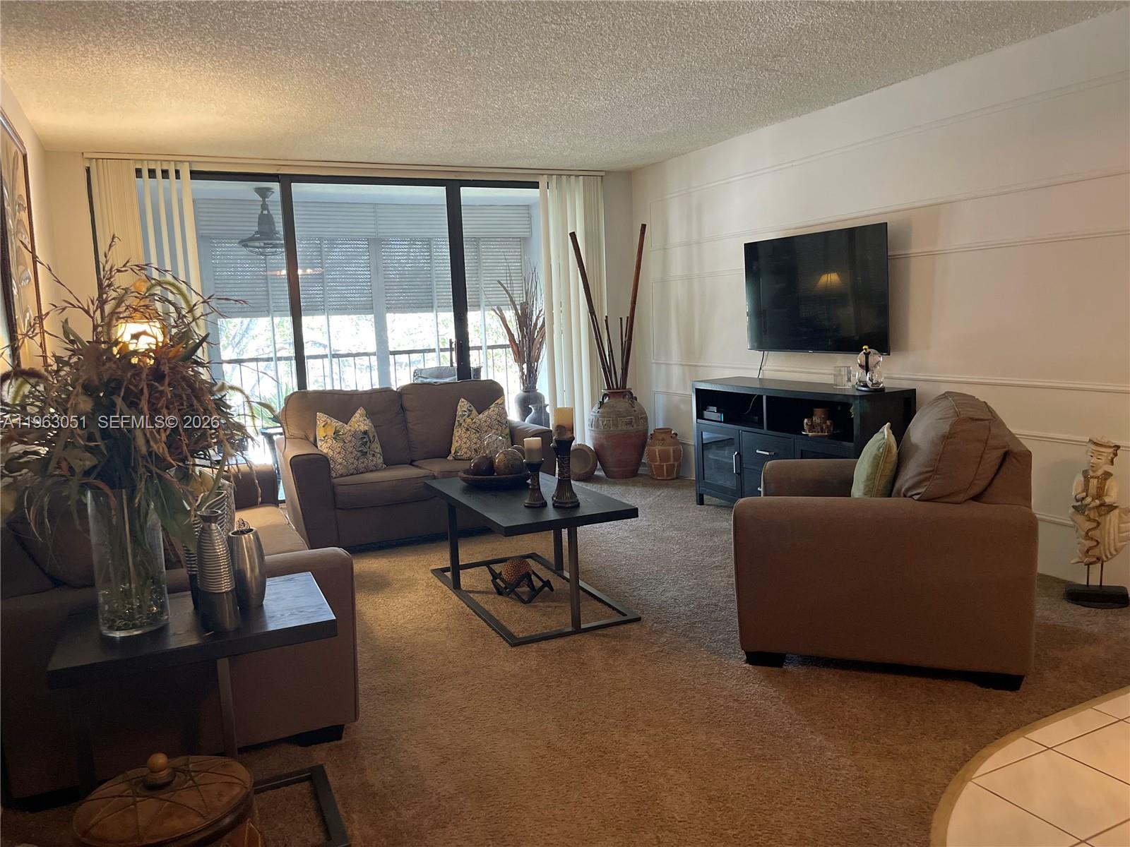 16475 Golf Club Road, Unit 309 Weston, FL 33326 - Photo 8 of 36 a living room with furniture and a flat screen tv