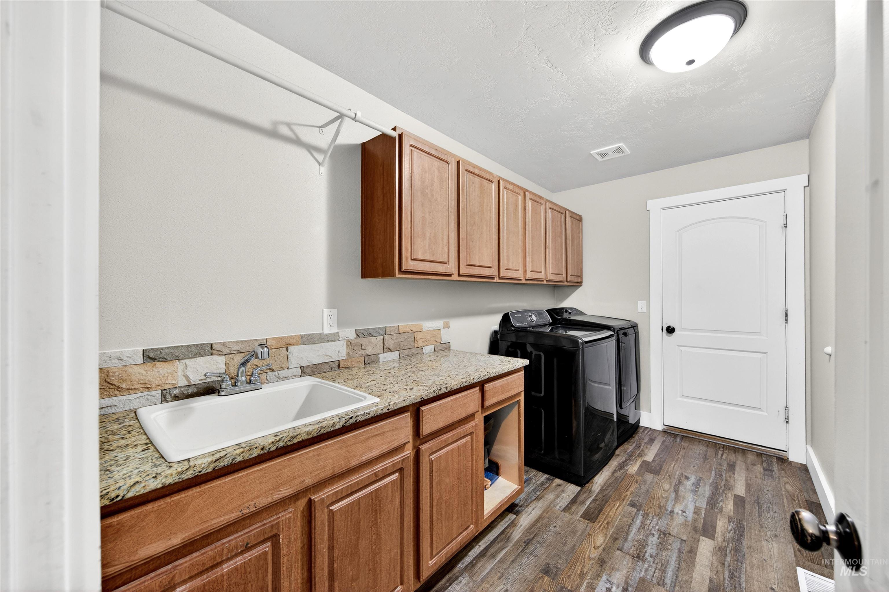 4 Round Up Circle Boise, ID 83716 - Photo 38 of 47 Functional laundry space featuring wood-finish flooring, light tan cabinetry, a light-colored countertop, and a utility sink with a chrome faucet