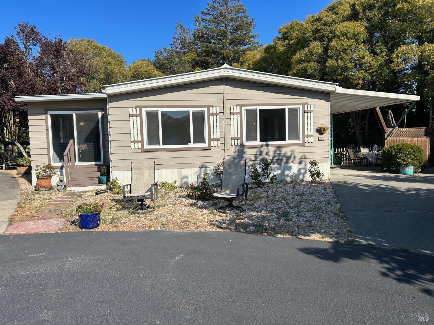 a backyard of a house with potted plants and large tree