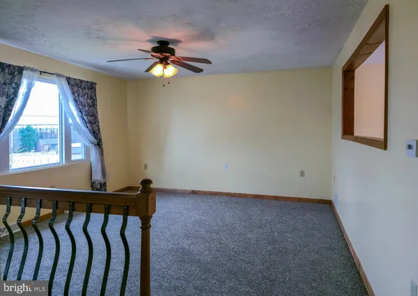 an empty room with windows and fan