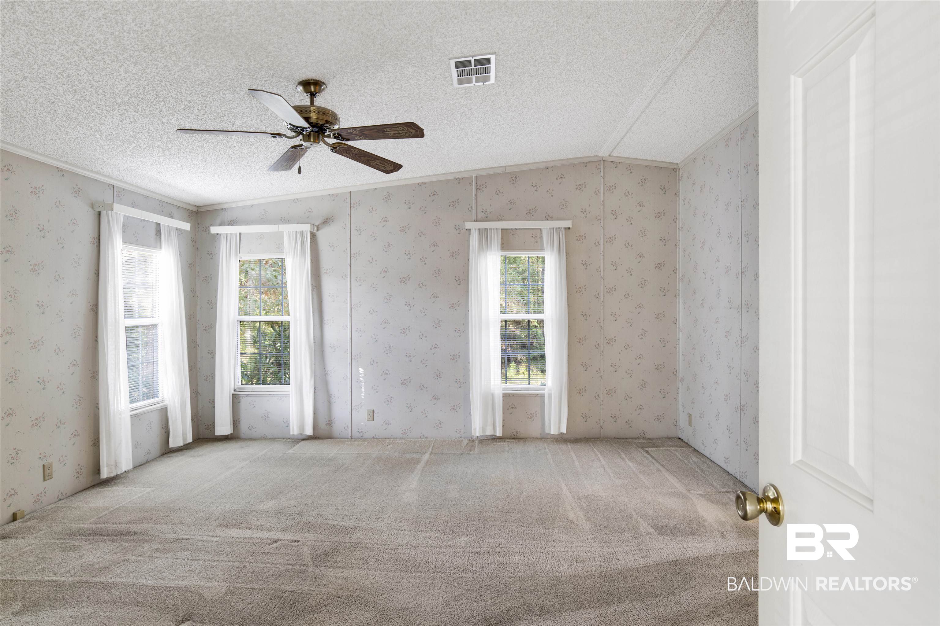 1216 Ridgewood Drive Lillian, AL 36549 - Photo 10 of 29 Empty room featuring a textured ceiling, ornamental molding, carpet, wallpapered walls, and a ceiling fan