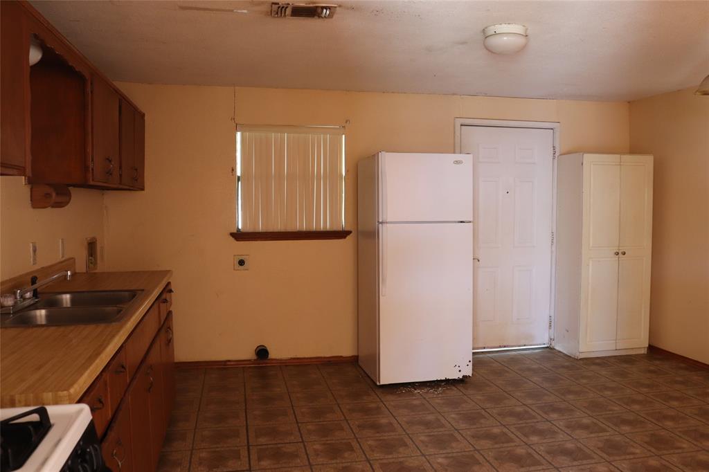 916 Poindexter Avenue Cleburne, TX 76033 - Photo 5 of 10 a kitchen with a refrigerator and a sink