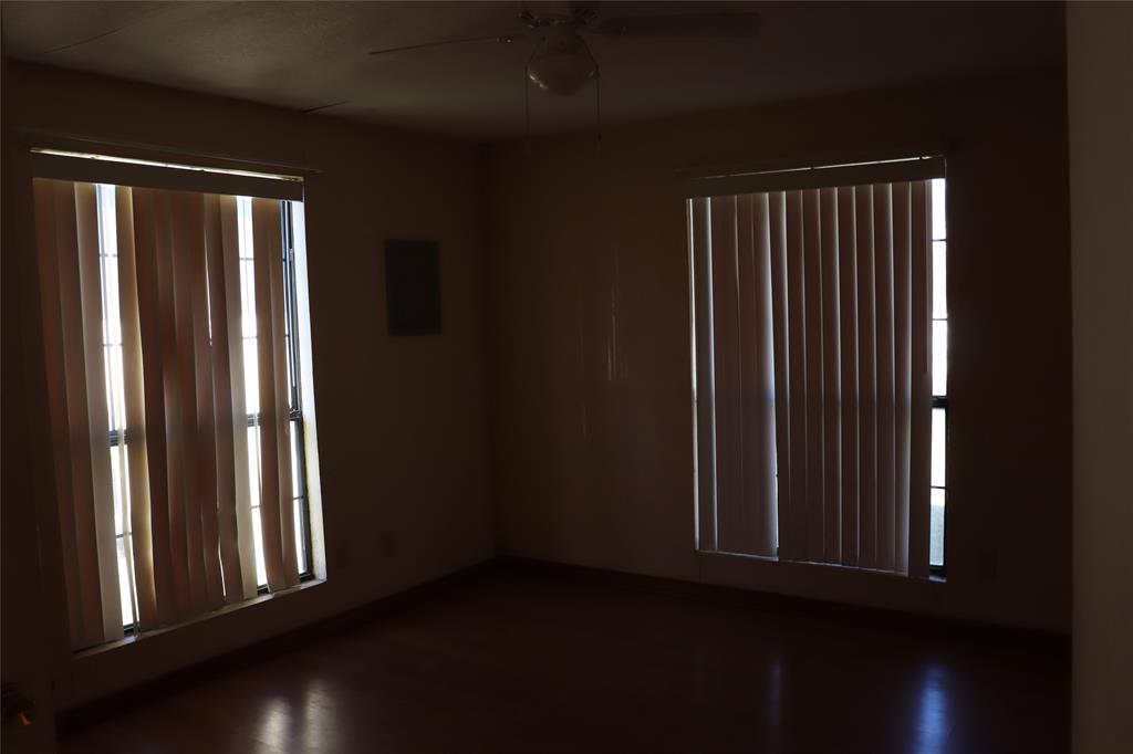 916 Poindexter Avenue Cleburne, TX 76033 - Photo 8 of 10 an empty room with wooden floor and windows
