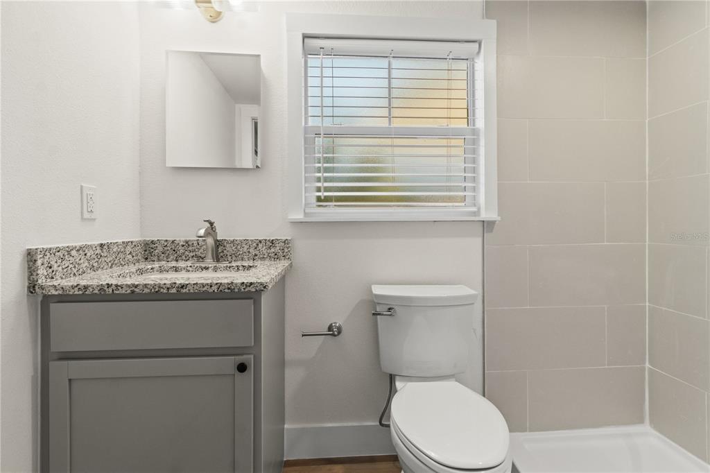 14348 Graham Street Dade City, FL 33523 - Photo 18 of 36 a bathroom with a granite countertop toilet sink and mirror