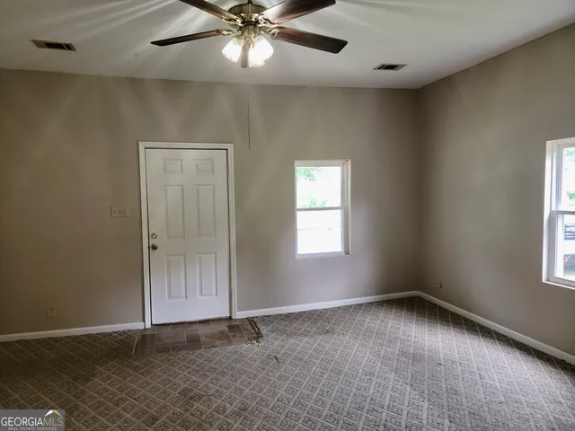 an empty room with windows and fan