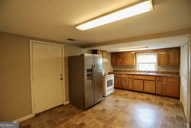 a kitchen with stainless steel appliances granite countertop a refrigerator and a stove top oven