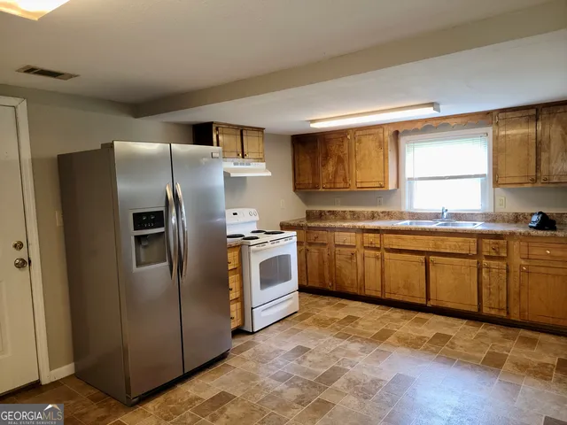 a kitchen with stainless steel appliances granite countertop a stove a sink dishwasher a refrigerator and cabinets with wooden floor