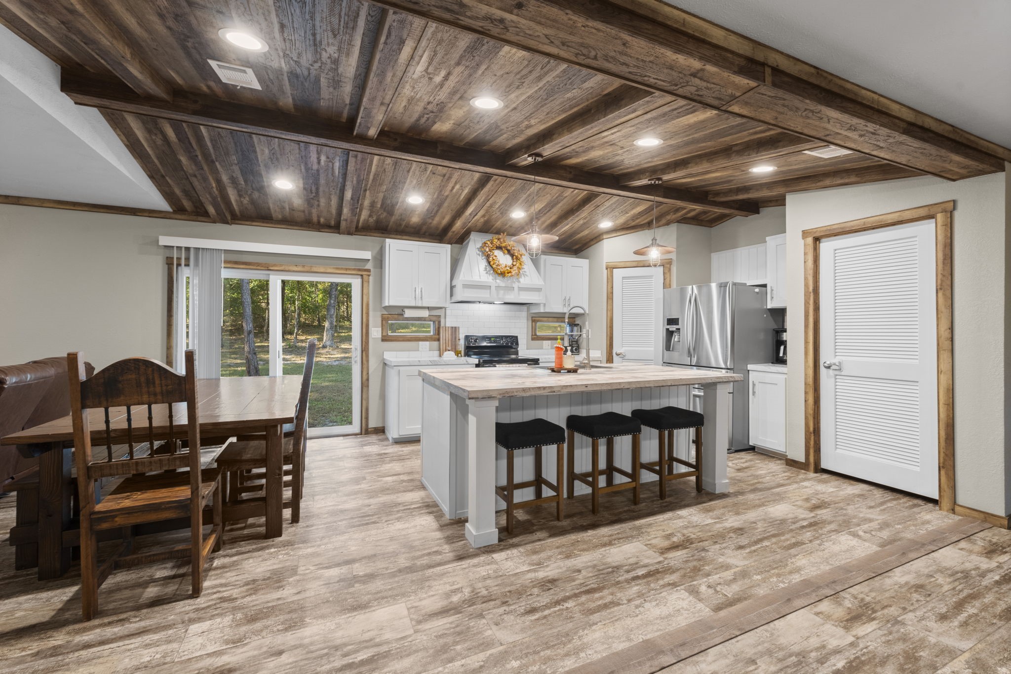 577 Winding River Road South Oakhurst, TX 77359 - Photo 10 of 31 a large kitchen with stainless steel appliances granite countertop a stove a refrigerator a dining table and chairs with wooden floor