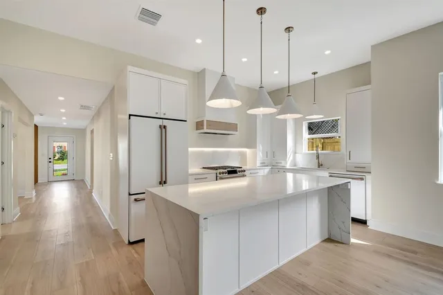 a kitchen with stainless steel appliances granite countertop a sink a refrigerator and a stove