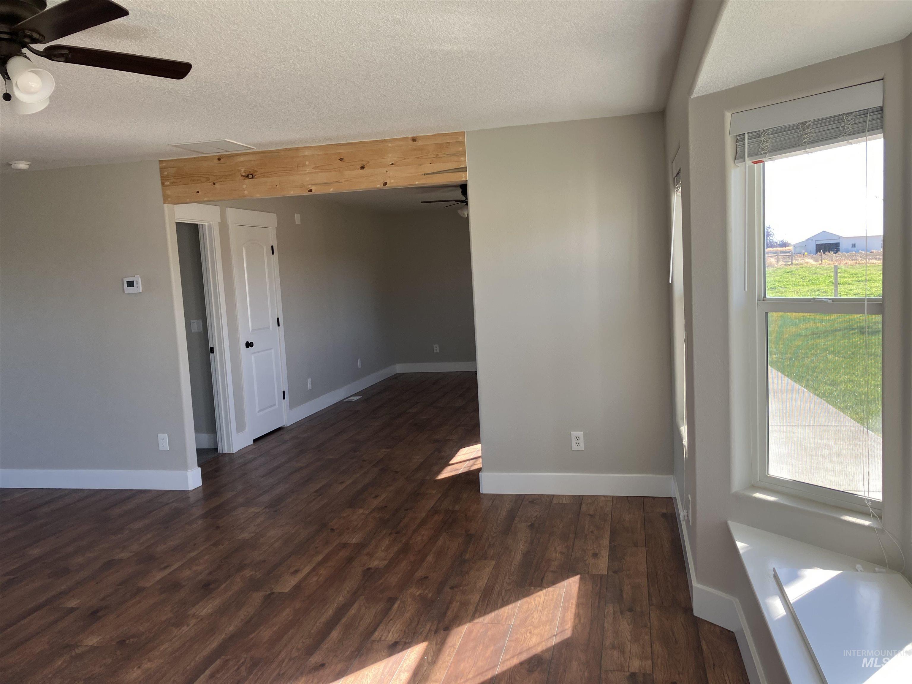 17530 Beet Road Caldwell, ID 83607 - Photo 12 of 50 Unfurnished room featuring dark wood-style flooring, ceiling fan, and a textured ceiling
