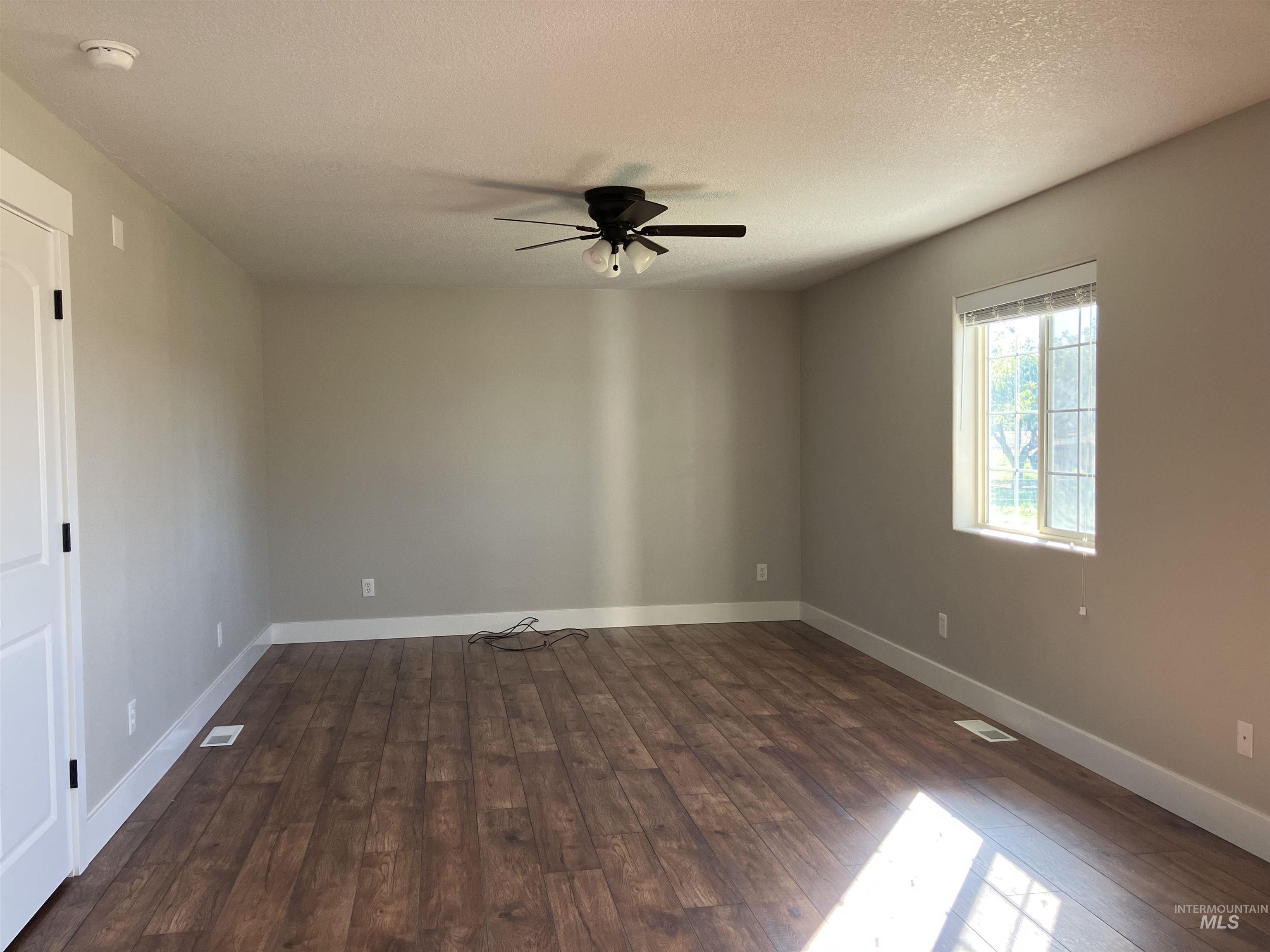 17530 Beet Road Caldwell, ID 83607 - Photo 16 of 50 Spare room with a textured ceiling, dark wood-style floors, and a ceiling fan