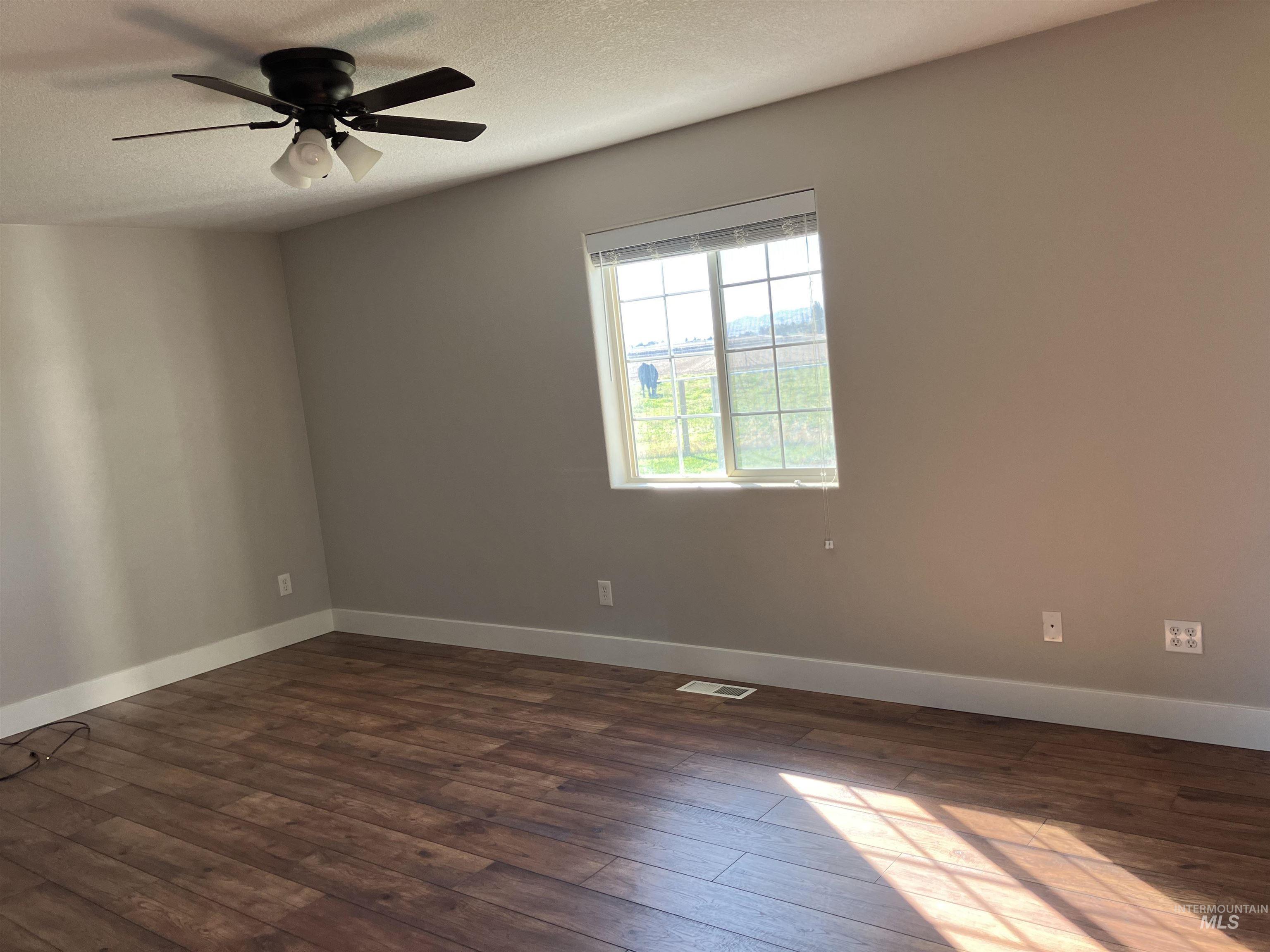 17530 Beet Road Caldwell, ID 83607 - Photo 17 of 50 Unfurnished room with dark wood finished floors, a textured ceiling, and a ceiling fan