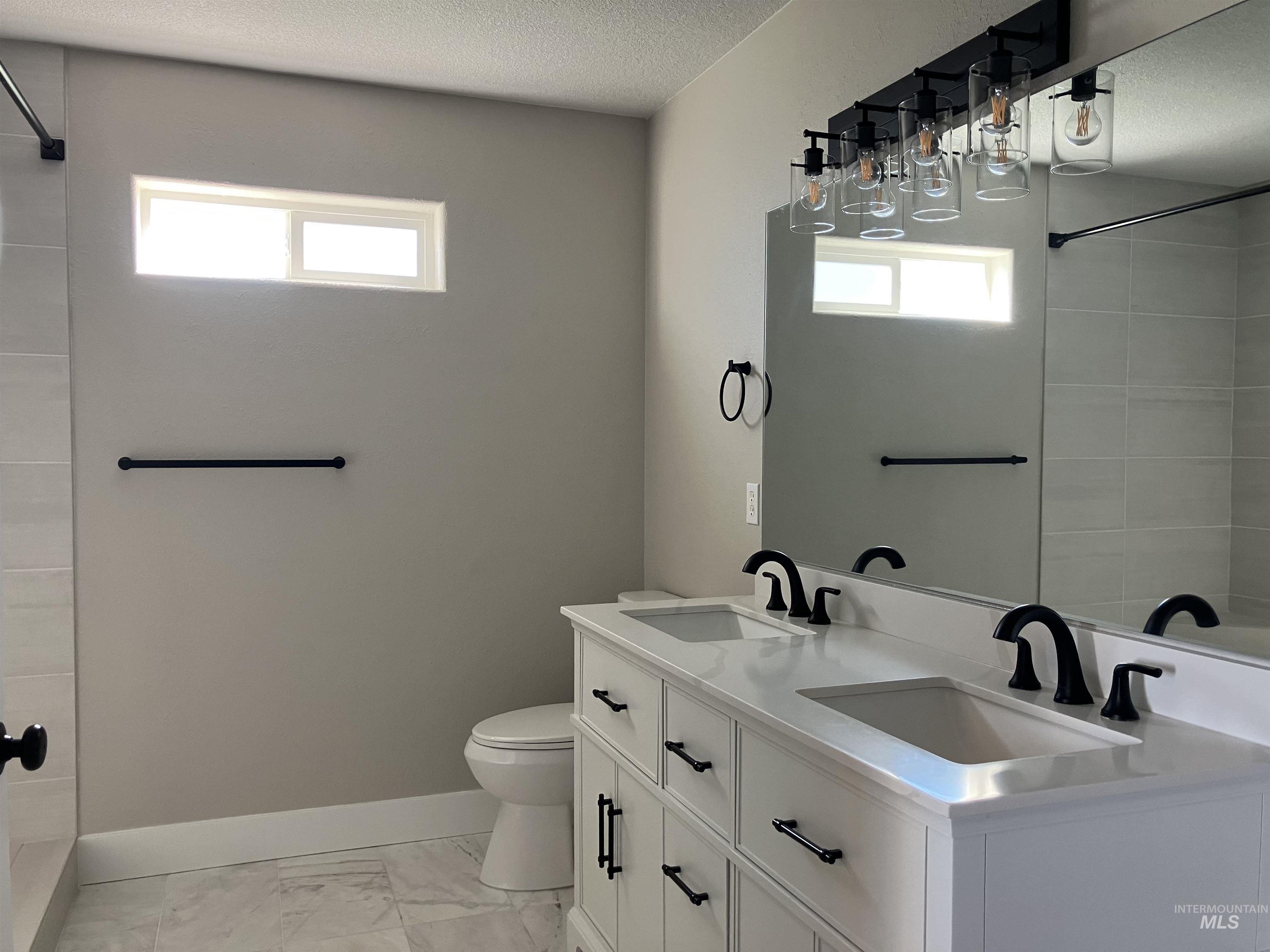 17530 Beet Road Caldwell, ID 83607 - Photo 21 of 50 Bathroom with double vanity, light marble finish flooring, a textured ceiling, and tiled shower / bath combo