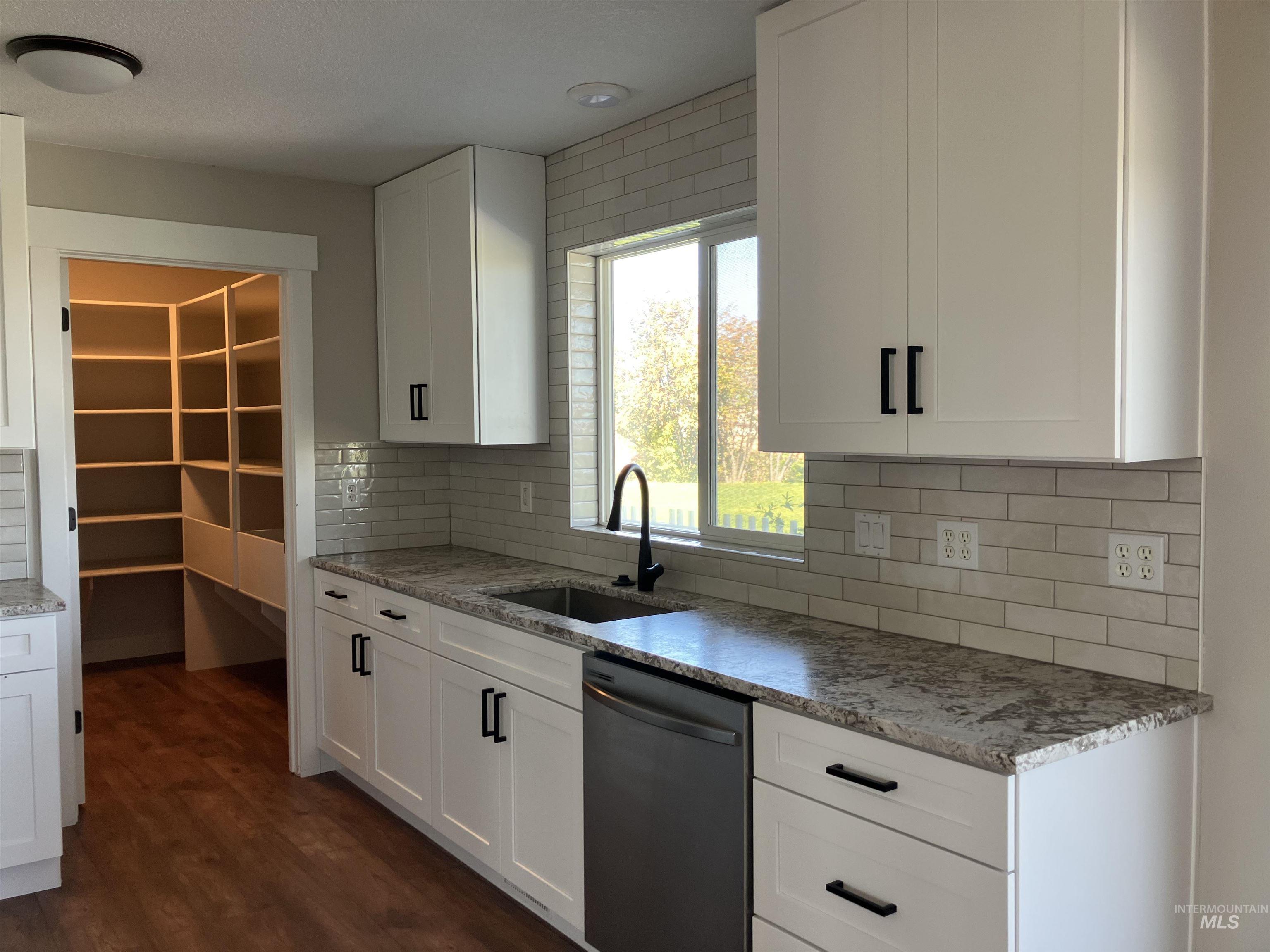 17530 Beet Road Caldwell, ID 83607 - Photo 26 of 50 Kitchen featuring stainless steel dishwasher, light stone counters, white cabinets, tasteful backsplash, and dark wood-style floors