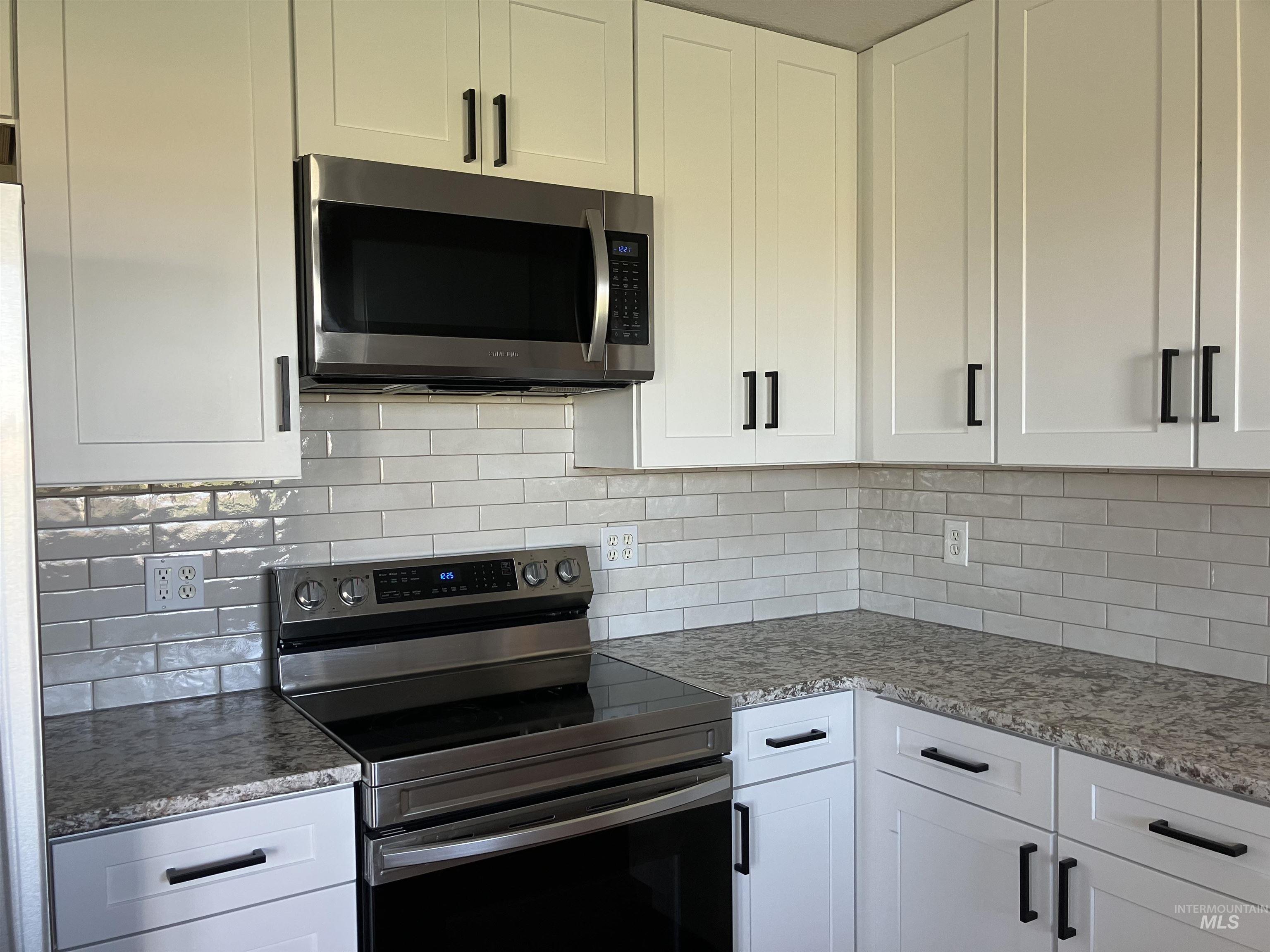 17530 Beet Road Caldwell, ID 83607 - Photo 27 of 50 Kitchen with stainless steel appliances, white cabinets, and light stone counters