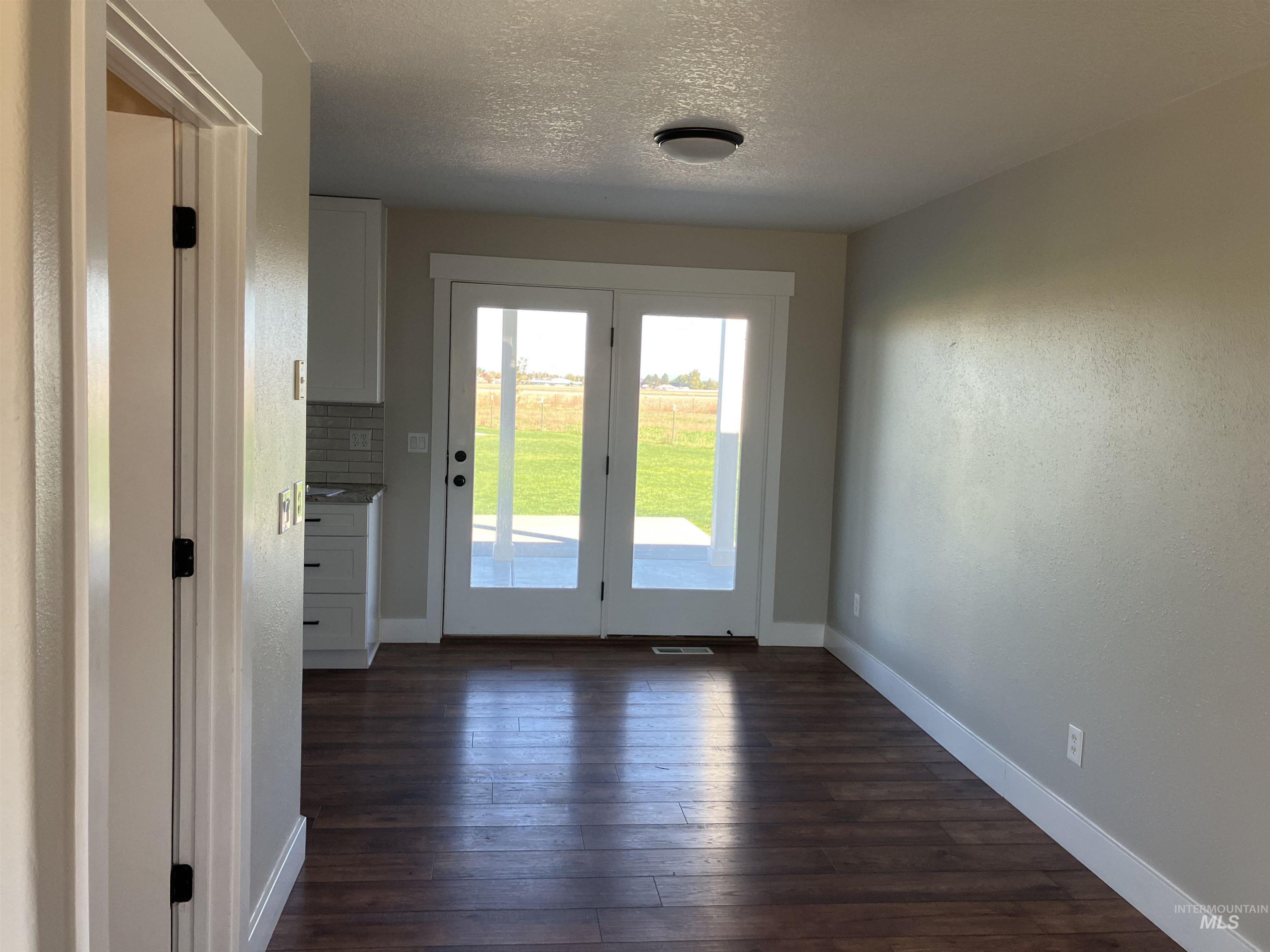 17530 Beet Road Caldwell, ID 83607 - Photo 31 of 50 Doorway to outside featuring a textured ceiling, hardwood / wood-style flooring, and a textured wall