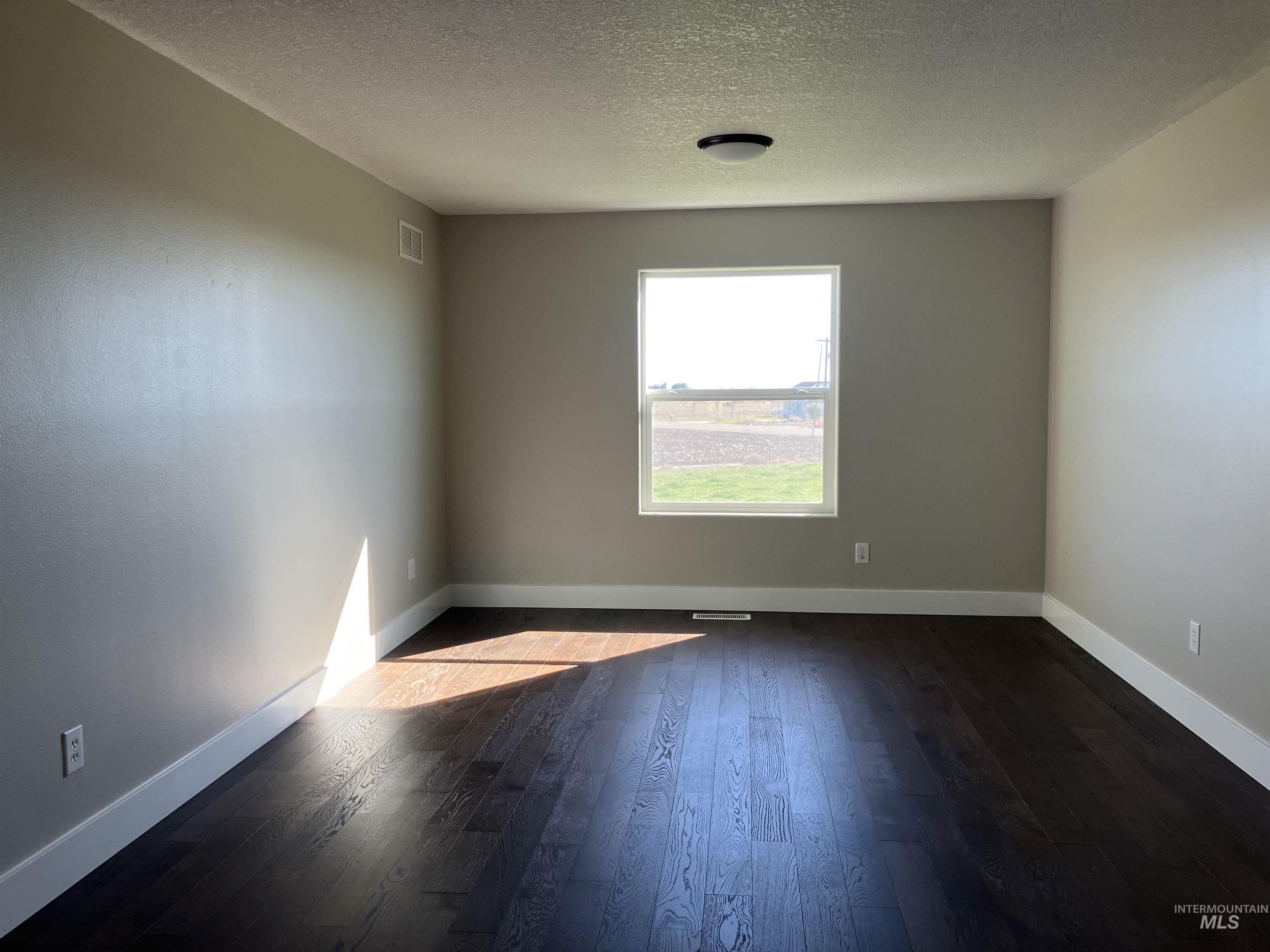 17530 Beet Road Caldwell, ID 83607 - Photo 36 of 50 Bedroom with dark wood-style floors and a textured ceiling and a 8' x 19' "closet". Or could be a bonus room.