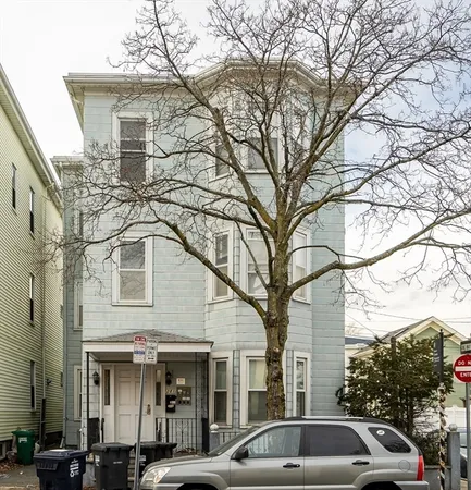 a view of a white house with a large tree