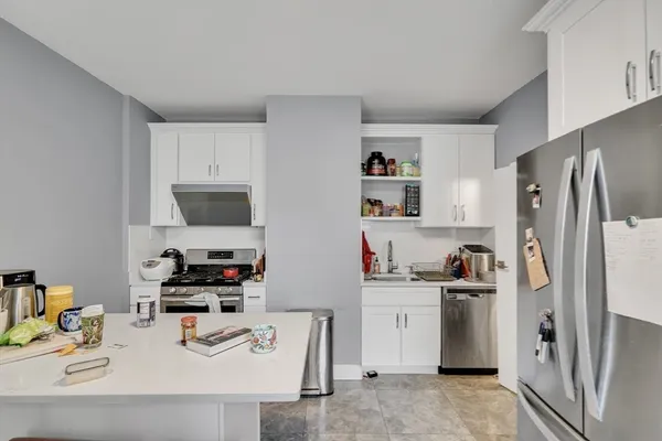a kitchen with stainless steel appliances a sink a refrigerator and a counter top space