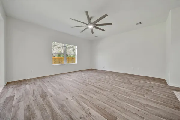a view of an empty room with window and wooden floor
