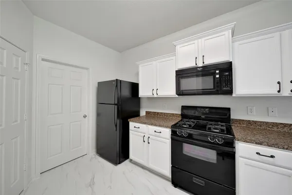 a kitchen with a refrigerator stove and white cabinets