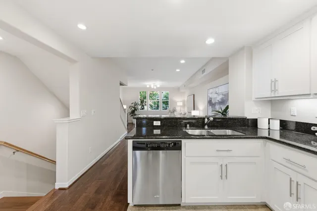 a kitchen with stainless steel appliances a refrigerator a stove a sink and white cabinets