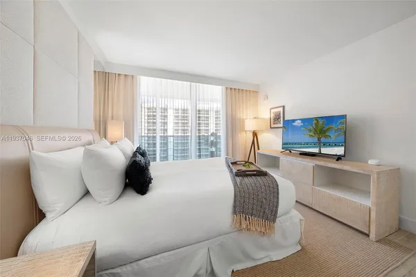 a bedroom with a bed and large windows