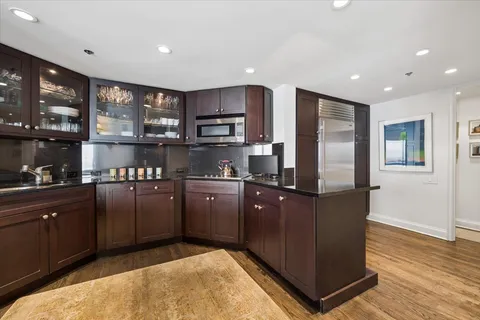 a kitchen with stainless steel appliances granite countertop a refrigerator a stove and a sink with wooden cabinets