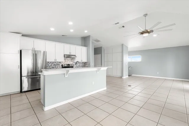 a view of a kitchen with kitchen island stainless steel appliances a refrigerator sink and cabinets