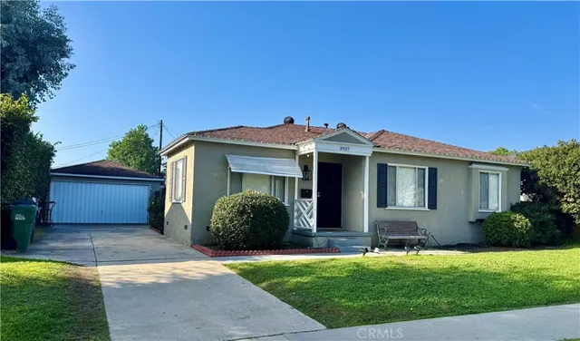 a view of a house with a yard potted plants and a table