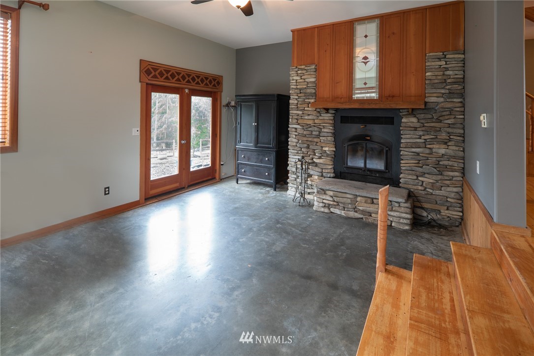 3399 East Harbor Road Langley, WA 98260 - Photo 23 of 36 an empty room with wooden floor a fireplace and windows