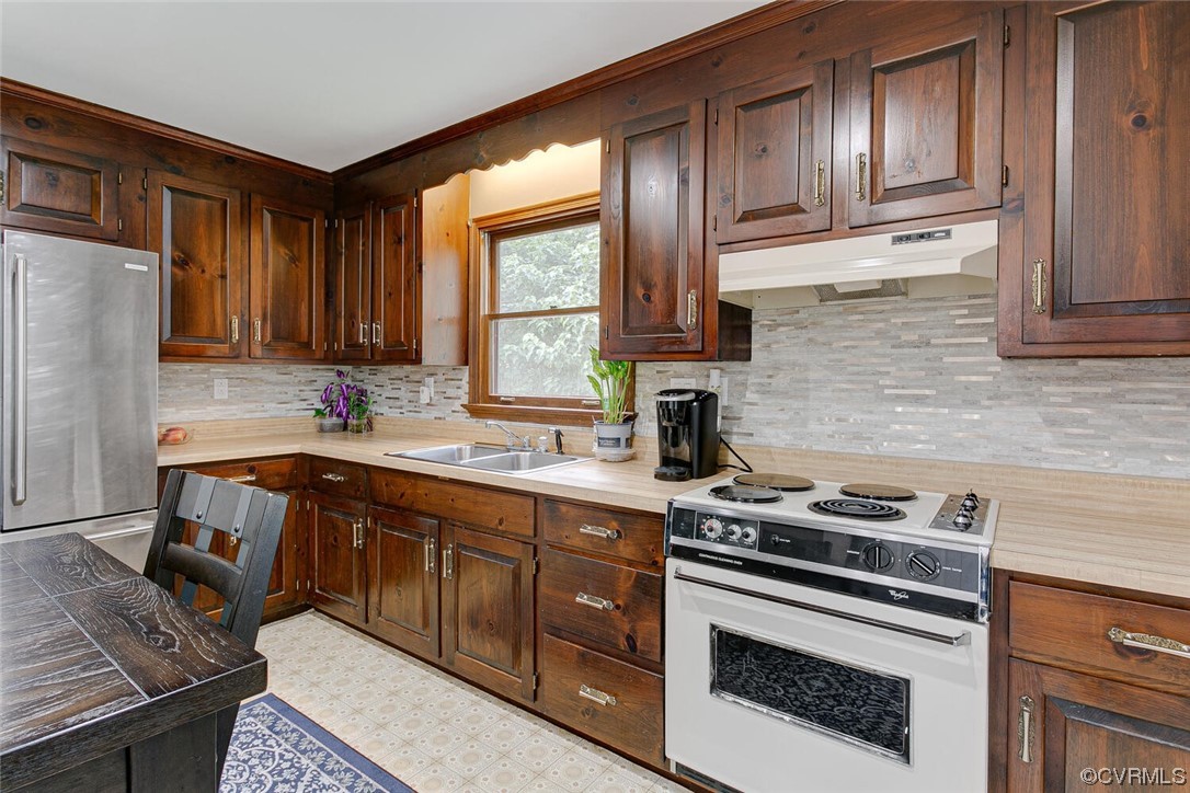 2125 Briarcliff Road Richmond, VA 23225 - Photo 7 of 27 Kitchen featuring light tile flooring, dark brown cabinets, backsplash, stainless steel refrigerator, light countertops, and white electric stove