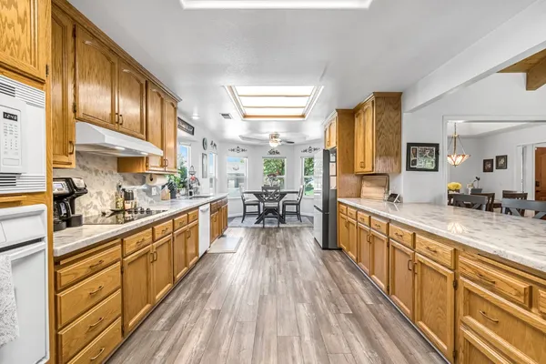 a large kitchen with stainless steel appliances granite countertop a lot of counter space and wooden floors